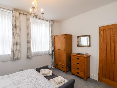 A bedroom with a bed a wooden wardrobe a chest of drawers and a mirror at The Bungalow in Whitby