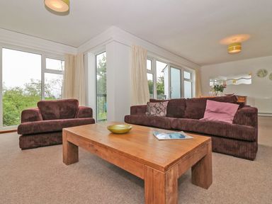 A living room with brown sofas and a wooden coffee table by large windows at Tamar Cottages 35 St Ann's Chapel Cornwall