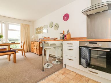 A kitchen and dining area with a dining table chairs bar stools oven and wooden sideboard at Tamar Cottages 35 in St Ann's Chapel Cornwall