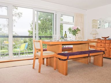 A dining room with wooden table chairs bench and floral centerpiece at Tamar Cottages 35 in St Ann's Chapel Cornwall