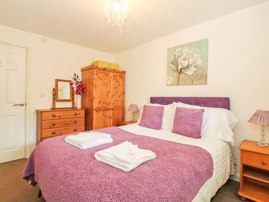 A bedroom with a double bed covered in purple bedding and white towels on top at Tamar Cottages 35 in St Ann's Chapel Cornwall