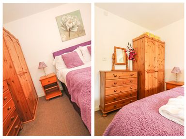 A bedroom with wooden wardrobes a chest of drawers a bed with purple bedding and a bedside table with a lamp at Tamar Cottages 35 in St Ann's Chapel Cornwall