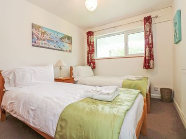 A bedroom with two single beds a bedside table and a window at Tamar Cottages 35 St Ann's Chapel Cornwall
