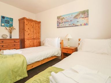 A bedroom with two single beds wooden wardrobe chest of drawers and nightstand with lamp at Tamar Cottages 35 St Ann's Chapel Cornwall