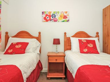 A bedroom with two single beds a wooden nightstand and a lamp at Tamar Cottages 35 St Ann's Chapel Cornwall