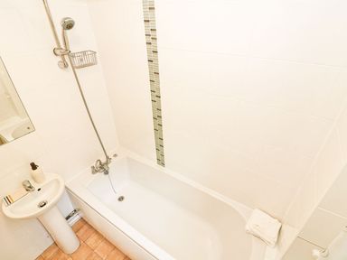 A bathroom with a white bathtub shower and sink at Tamar Cottages 35 in St Ann's Chapel Cornwall