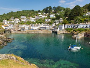 A coastal village with houses on a hillside overlooking a harbor with a sailboat in the water at Tamar Cottages 35 in St Ann's Chapel Cornwall
