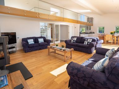 A living room with blue sofas a wooden coffee table and a dining area at Moult Hill Barn in Salcombe