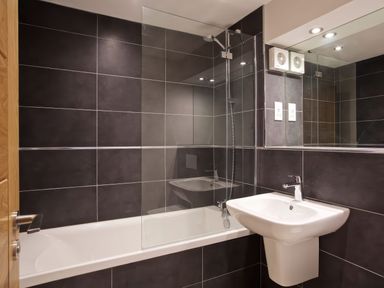 A bathroom with a bathtub shower and a wall-mounted sink at Moult Hill Barn in Salcombe