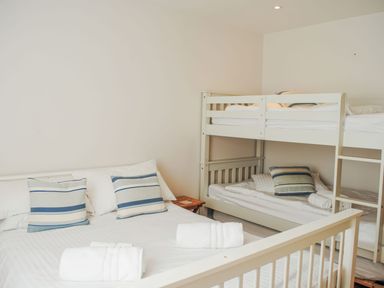 A bedroom with a double bed and a bunk bed with striped cushions at Moult Hill Barn in Salcombe