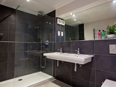 A bathroom with a walk in shower and a double sink at Moult Hill Barn in Salcombe