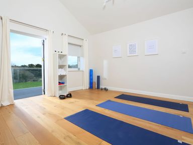 A yoga room with three exercise mats dumbbells and rolled towels on shelves at Moult Hill Barn in Salcombe