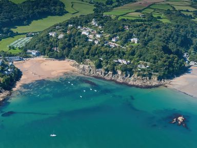 An aerial view of a coastal area with sandy beaches boats in the water and houses surrounded by trees at Moult Hill Barn in Salcombe