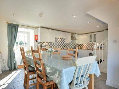 A kitchen with a dining table covered with a polka dot tablecloth and wooden chairs at Croft Cottage in Alnwick