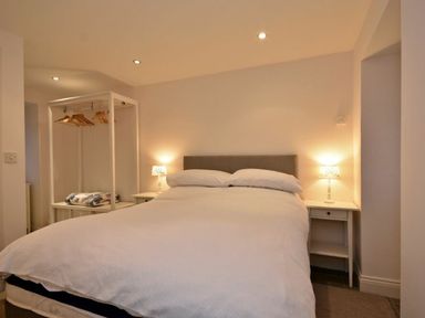 A bedroom with a double bed two bedside tables with lamps and an open wardrobe at Croft Cottage in Alnwick