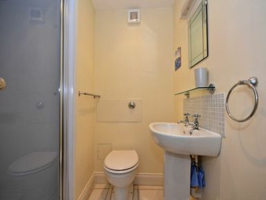 A small bathroom with a toilet and sink next to a glass shower door at Croft Cottage Alnwick