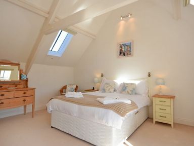 A bedroom with a bed bedside tables a dresser and a skylight window at Croft Cottage in Alnwick