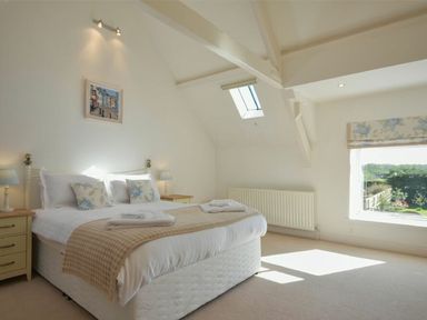 A bedroom with a bed two bedside tables lamps a window and a skylight at Croft Cottage Alnwick