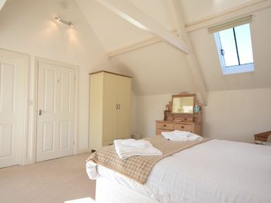 A bedroom with a bed towels on it a wardrobe dresser with a mirror and a skylight window at Croft Cottage in Alnwick