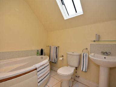 A bathroom with a bathtub toilet and sink with towels at Croft Cottage in Alnwick