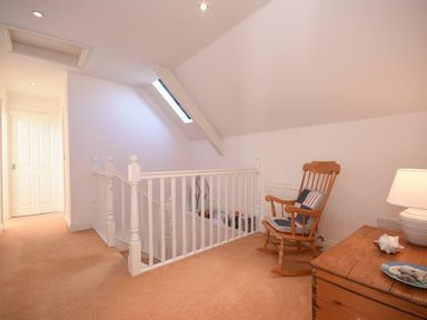 A landing area with a wooden rocking chair a wooden chest and a white railing at Croft Cottage in Alnwick