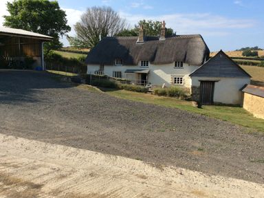 A cottage with a thatched roof and farm building at Westacombe Farm Dunsford near Tedburn St Mary