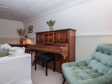 A living room with a piano and a chair at Westacombe Farm, Dunsford near Tedburn St Mary