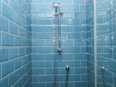 A shower with blue tiles and chrome fixtures at Westacombe Farm in Dunsford