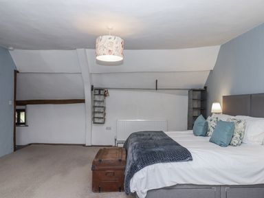 A bedroom with a bed and shelves at Westacombe Farm in Dunsford