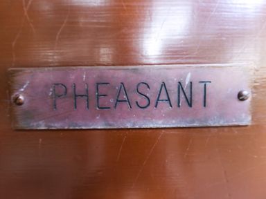 A close up of a metal nameplate with the word PHEASANT on a wooden surface at Pheasant Withern near Alford