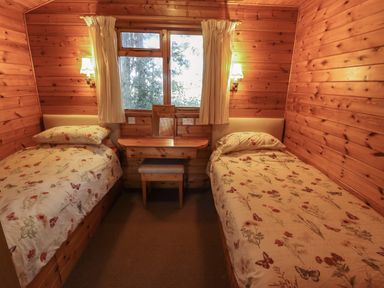 A wooden bedroom with two single beds a small desk and window at Pheasant Withern near Alford