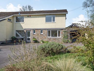 The exterior of a two story house with a mix of stone and yellow walls and various plants in front at Pant Y Cwtsh in Kidwelly