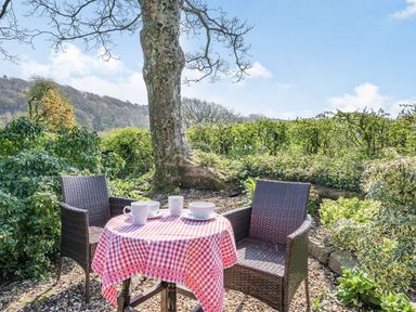 An outdoor seating area with two chairs and a table covered with a red and white checkered tablecloth at Pant Y Cwtsh in Kidwelly