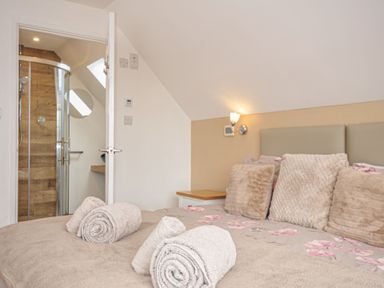 A bedroom with towels on a bed and a shower in the corner at Kernyk in Camelford