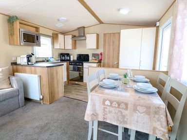 A kitchen and dining area with a table set for four near a window at Oakley Retreat in Fritton near Belton