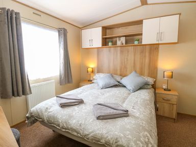A bedroom with a double bed two bedside tables and lamps wall cabinets and a window with curtains at Oakley Retreat in Fritton near Belton