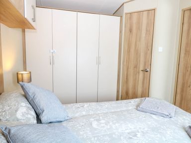 A bedroom with a bed and pillows a wardrobe and wooden doors at Oakley Retreat in Fritton near Belton
