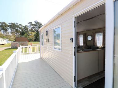 An exterior view of a mobile home with an open door leading to a living area at Oakley Retreat in Fritton near Belton