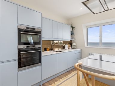 A kitchen with built-in ovens a sink countertop cabinets and a window with sea view at No 10 Croft House in Tenby