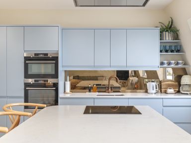 A kitchen with light blue cabinets a built in double oven and a white countertop with a sink and a stove at No 10 Croft House in Tenby