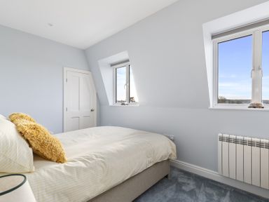 A bedroom with a bed near two windows and a closed door at No 10 Croft House in Tenby