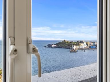 A window view of a coastal town with colorful buildings a pier and boats at No 10 Croft House in Tenby