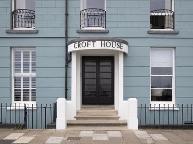 Front entrance of a building with blue walls black double doors and two windows at No 10 Croft House in Tenby
