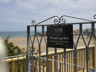 A metal gate with a sign reading private garden for Croft House guests with a beach and sea in the background at No 10 Croft House in Tenby