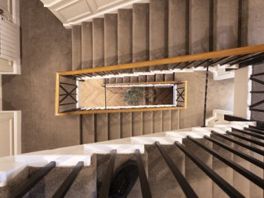 A multi-level staircase with carpeted steps black railings and a wooden handrail viewed from above at No 10 Croft House in Tenby