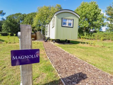 A shepherd's hut with a pathway and sign at Magnolia in Grimsby