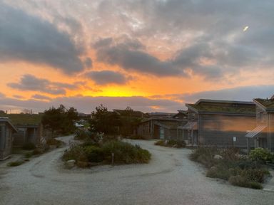 A residential area with wooden houses and gravel paths at sunset at Azure Retreat at Una in Carbis Bay near St Ives