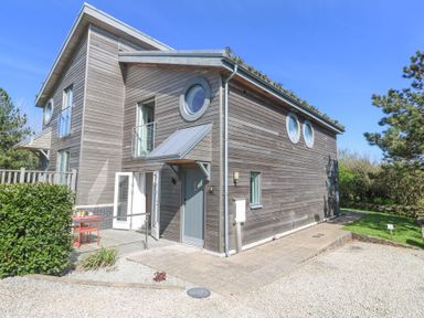 A wooden house with circular windows and an outdoor seating area at Azure Retreat at Una in Carbis Bay near St Ives