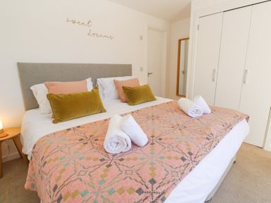 A bedroom with a double bed with pillows and rolled towels on a patterned blanket at Azure Retreat at Una in Carbis Bay near St Ives