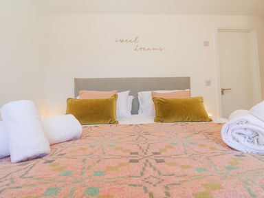 A bedroom with a bed covered by a patterned blanket with pillows and rolled towels at Azure Retreat at Una Carbis Bay near St Ives